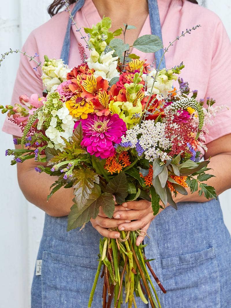 Gardener holding a bouquet of freshly harvested flowers.