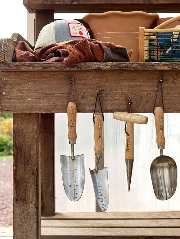 hats on a bench with gardening tools