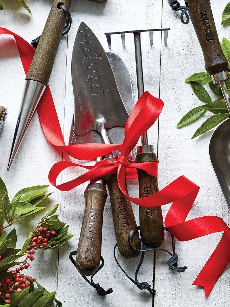 A wrapped present with gardening tools on top.