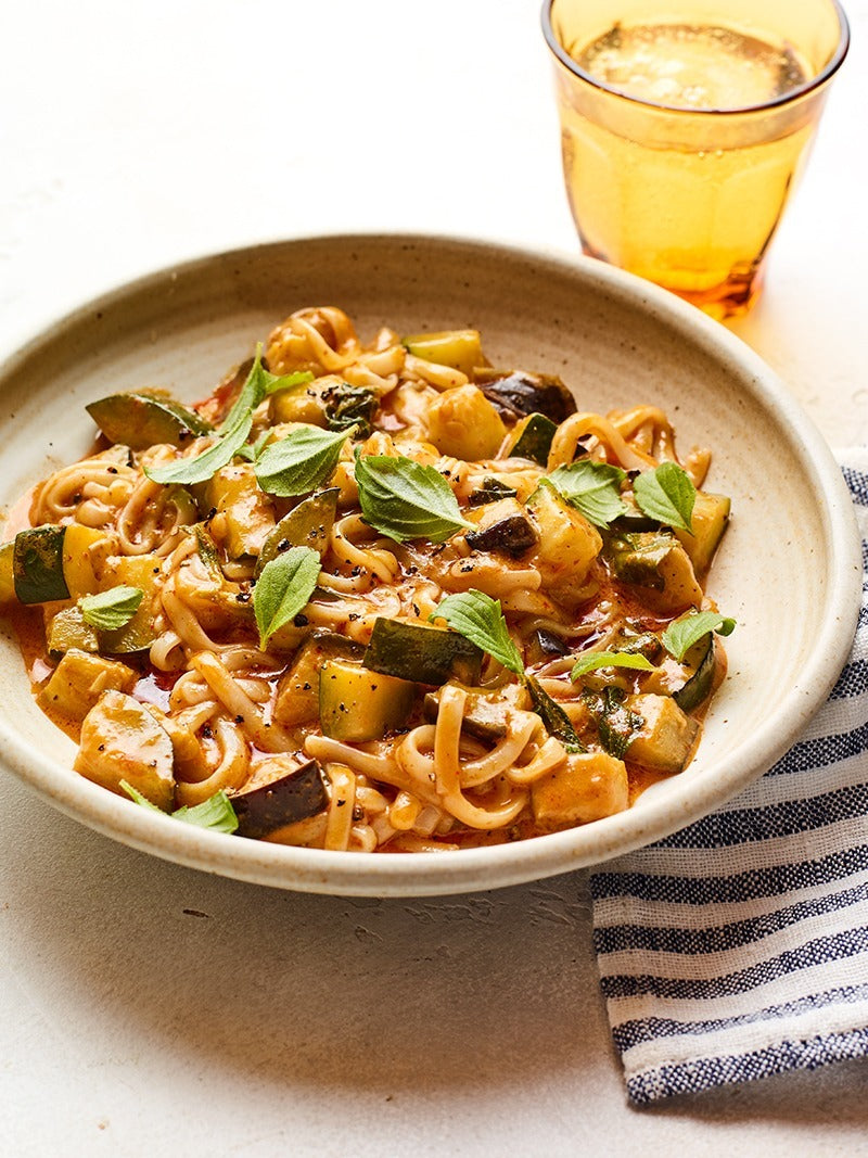 A plate of vegetable curry noodles with thai basil.